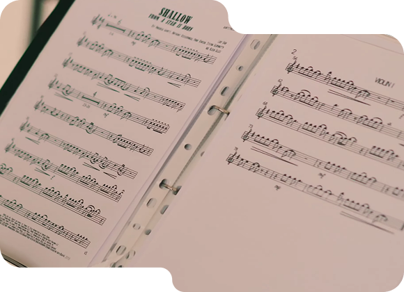 Open binder with sheet music titled 'Shallow' and musical notes on both visible pages.